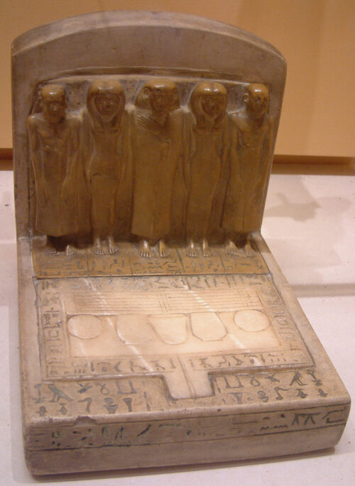 Statue group and offering table, Abydos, Louvre 228. The offering table is in the shape of the hetep hieroglyph, and it has a hetep hieroglyph depicted in its center (both upside down to the viewer). Photo by Guillaume Blanchard, CC by-SA 3.0.