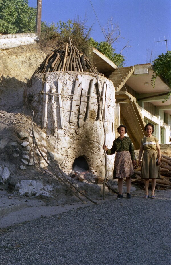 Sisters Rodou and Elpiniki posed in front of their top-loading kiln as a small fire burned in front of the firebox in Agios Demetrios. August 1986. Photo by the Author.