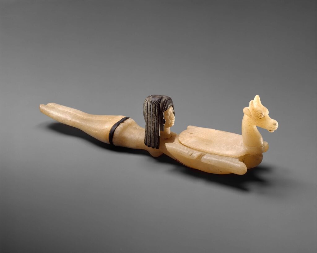 Fig. 4: Alabaster and steatite cosmetic spoon in the shape of a swimming girl holding a gazelle, New Kingdom, reign of Amenhotep III, ca. 1390–1353 BCE. (Metropolitan Museum of Art)