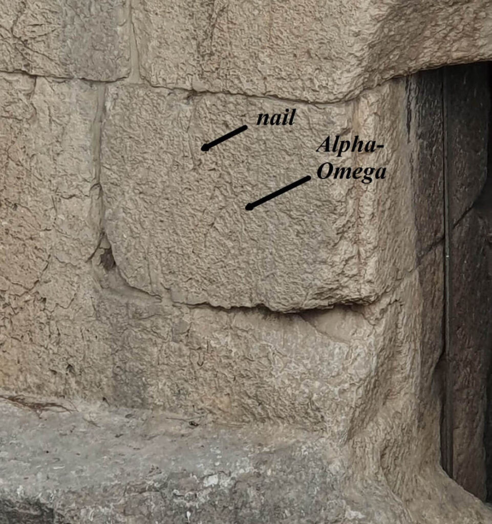 The ashlar block, left of the entrance, before the “squeeze”, showing an alpha, partial omega, and a nail. (Photo by Joe Zias)