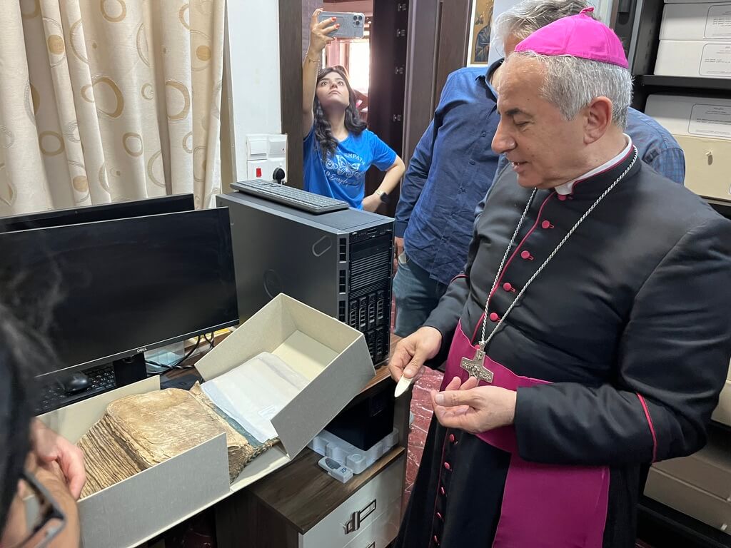 The director of Centre Numérique des Manuscrits d’Orientaux (CNMO), Archbishop Najeeb Michaeel, examines manuscripts to be digitized. Photo © Peter Herdrich.