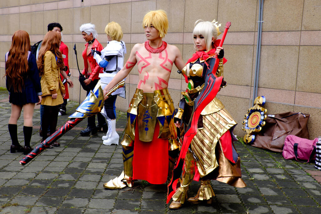 Cosplayers dressed up as characters from the video game Fate: Gilgamesh on the left, Nero Claudius on the right. Public Domain via Wikimedia Commons.