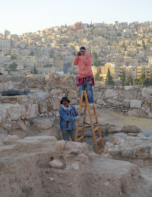 Excavation team members photographing the site with the urban neighborhoods of modern Amman in the background. ©Amman Archaeological Project (Münster University, DAI, Felix Wolter)