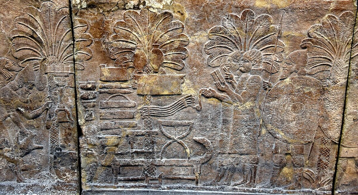 Assyrian scribes counting booty; the front scribe writes in cuneiform on a wax wooden board while the second scribe writes with ink and Aramaic alphabet on papyrus or leather. South-West Palace at Nineveh, 7th century, British Museum. Photo: Omsama Shukir Muhammed Amin FRCP (Glasg),  CC BY 4.0.