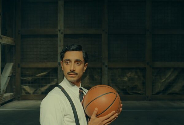 Prince Farouk (Riz Ahmed) shifts from regal confidence to uncertainty as he is compelled to participate in an awkward 2-on-2 basketball match to determine whether the railroad tunnel in his kingdom can be finished. Still image from The Phoenician Scheme (2025), directed by Wes Anderson. Courtesy of Focus Features.